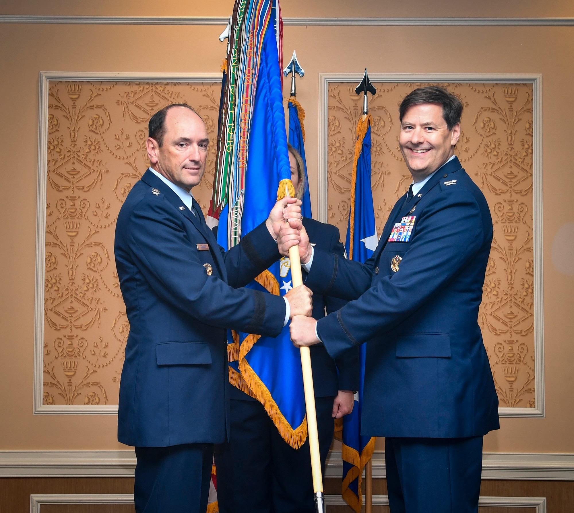 Two individuals hold a guidon for an Air Force Wing.