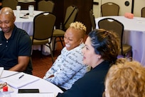 Family members laugh together during a group seminar. They are seated together at a table.