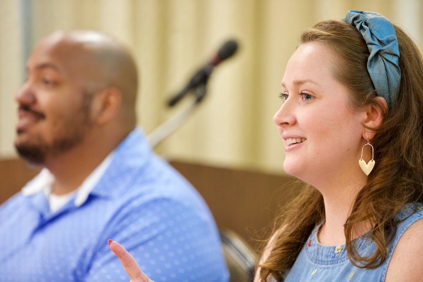 Kendra Adams-Venezario (right) and her husband, Chaplain (1st. Lt.) Carlos Joel Venezario (left), address Soldiers and families. Adams-Venezario is smiling.