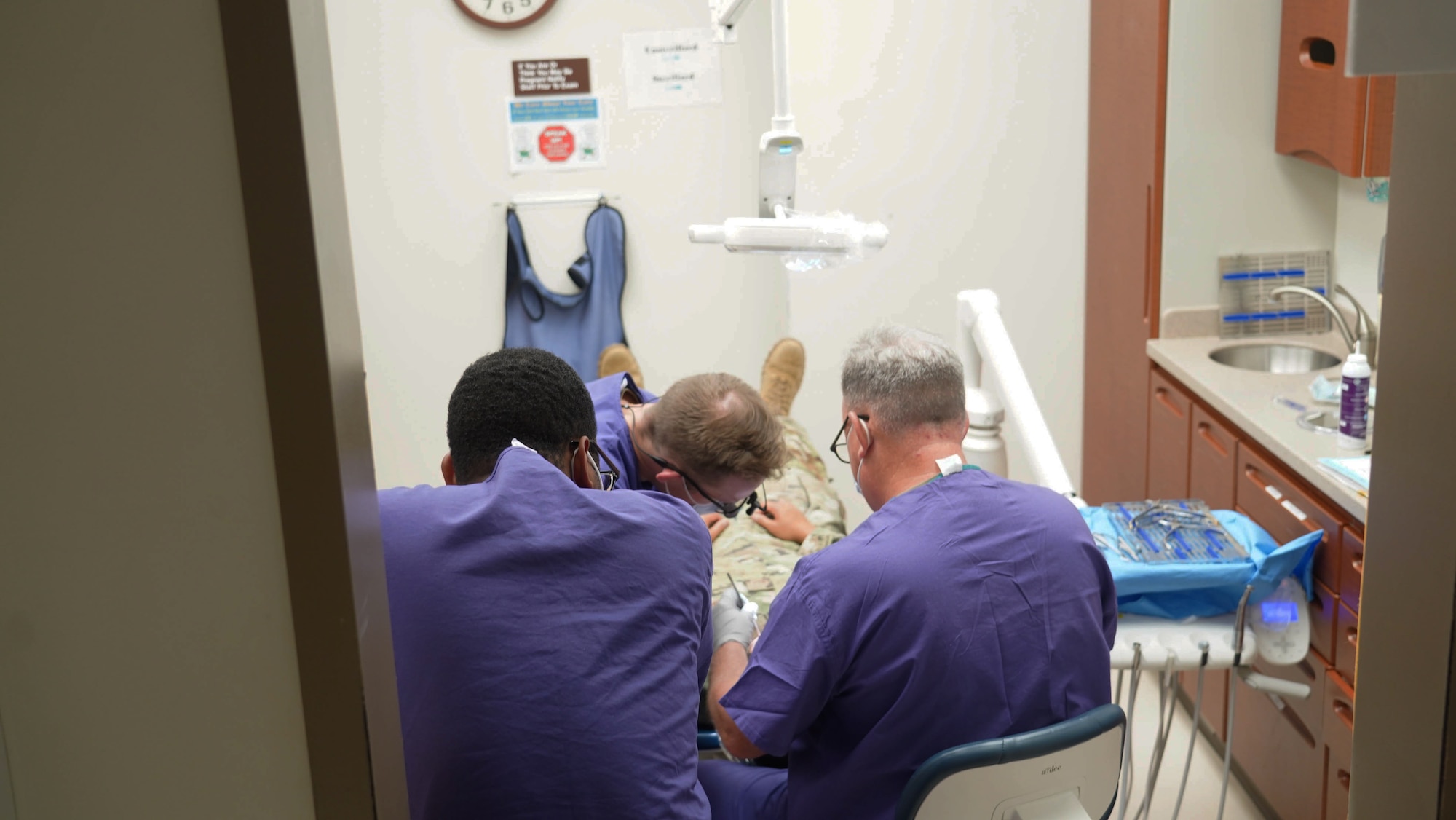 Four men sit in the middle of the photo, performing dental work.