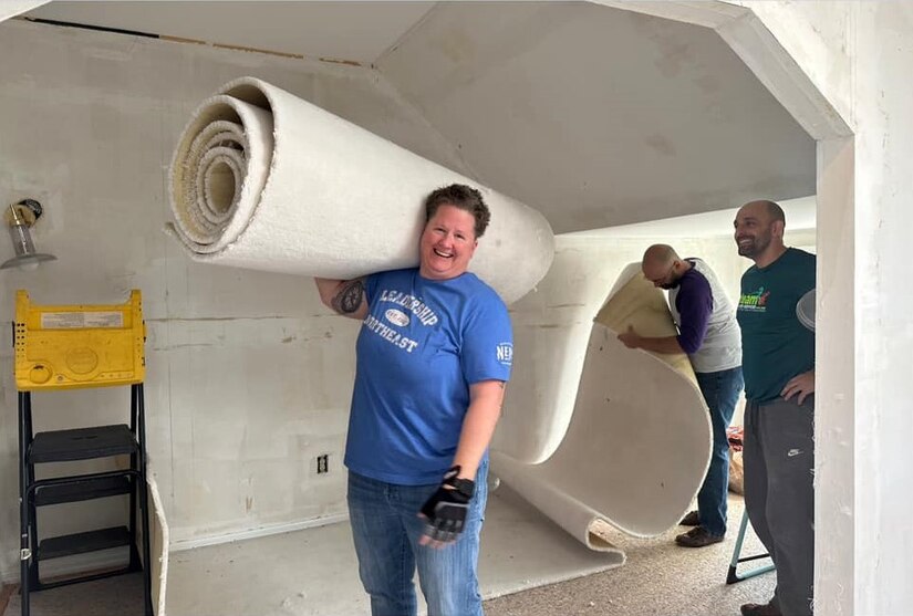 Photo of Therese Paxton caring a carpet during renovations