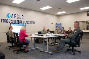 Airmen and civilians sitting around a table briefing