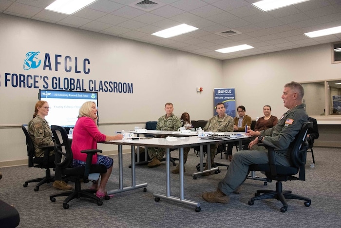 Airmen and civilians sitting around a table briefing