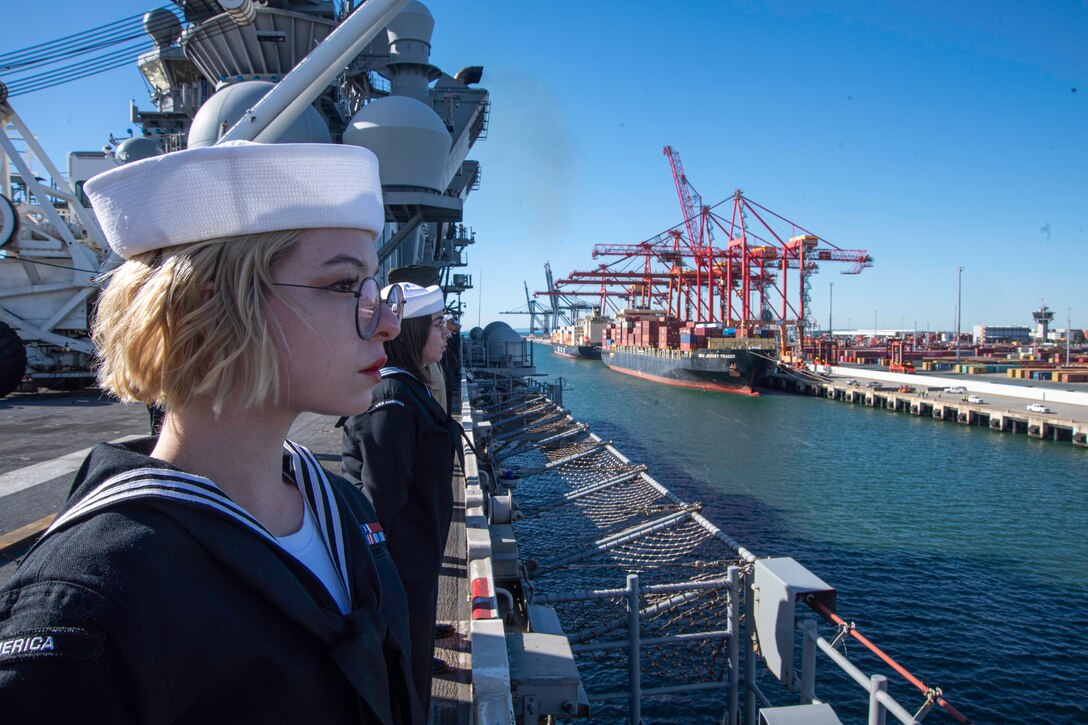 BRISBANE, Australia (June 20, 2023) Hospital Corpsman 3rd Class Marina Hernandez, from Columbus, Ohio, assigned to the forward-deployed amphibious assault carrier USS America (LHA 6) mans the rails as the ship prepares to conduct a scheduled port visit to Brisbane, Australia, June 20, 2023. America, lead ship of the America Amphibious Ready Group, is operating in the U.S. 7th Fleet area of operations. U.S. 7th Fleet is the U.S. Navy’s largest forward-deployed numbered fleet, and routinely interacts and operates with allies and partners in preserving a free and open Indo-Pacific region. (U.S. Navy photo by Mass Communication Specialist 2nd Class Cole Pursley)