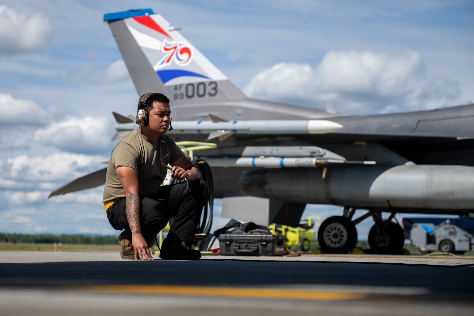 an 80th Fighter Generation Squadron crew chief  waits on a flight line near a Kunsan AB F-16 Fighting Falcon