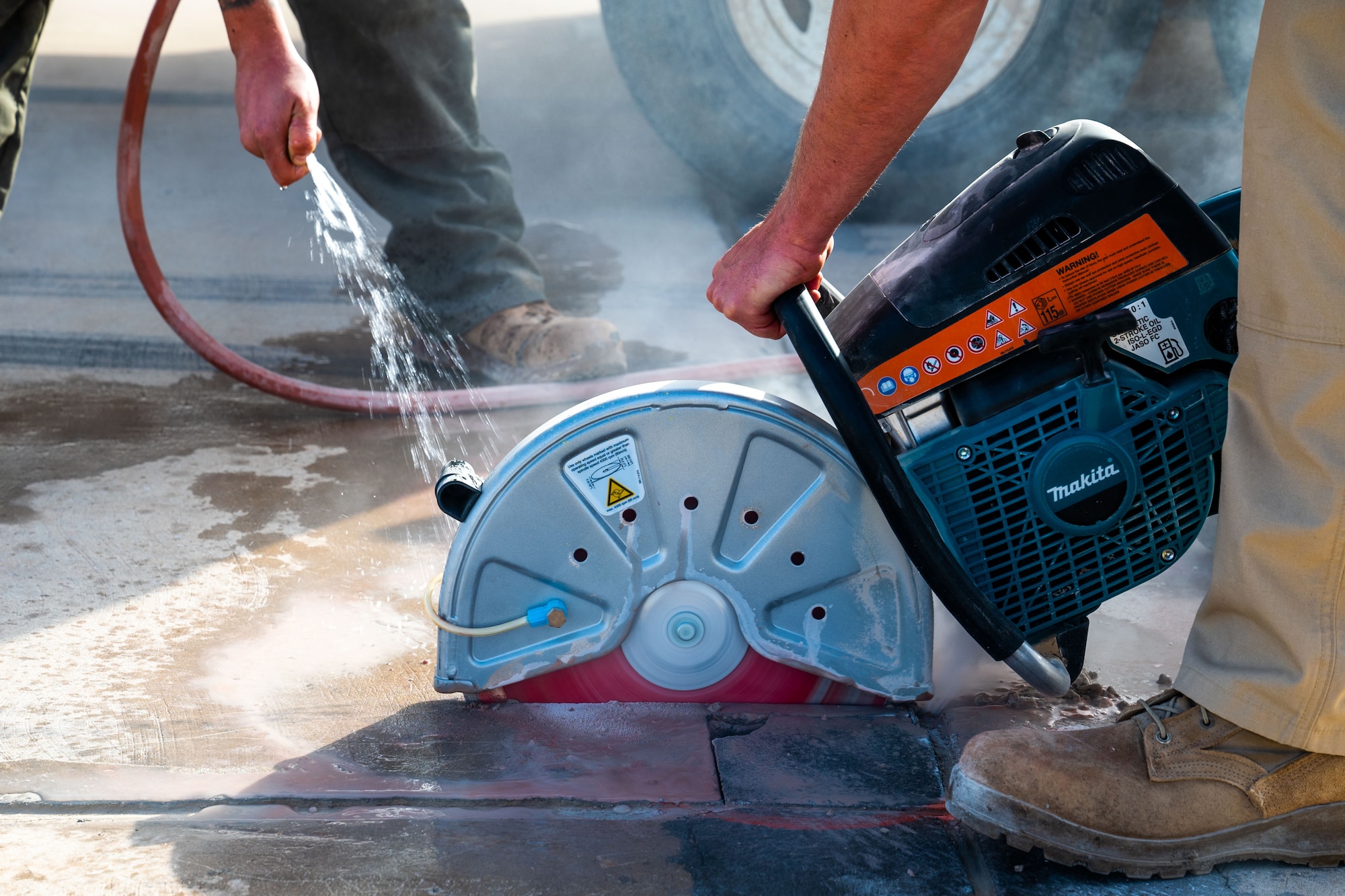 A man operates a concrete saw on a runway.