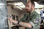 Man in UK military uniform writing on dry erase board with marker