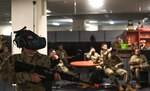 A U.S. Air Force Airman, holds a simulated weapon while training on a Virtual Reality headset