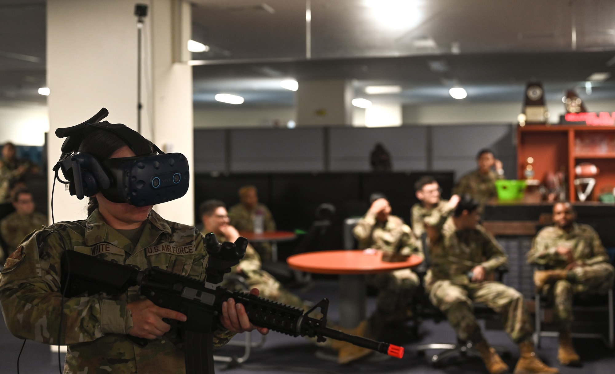 A U.S. Air Force Airman, holds a simulated weapon while training on a Virtual Reality headset