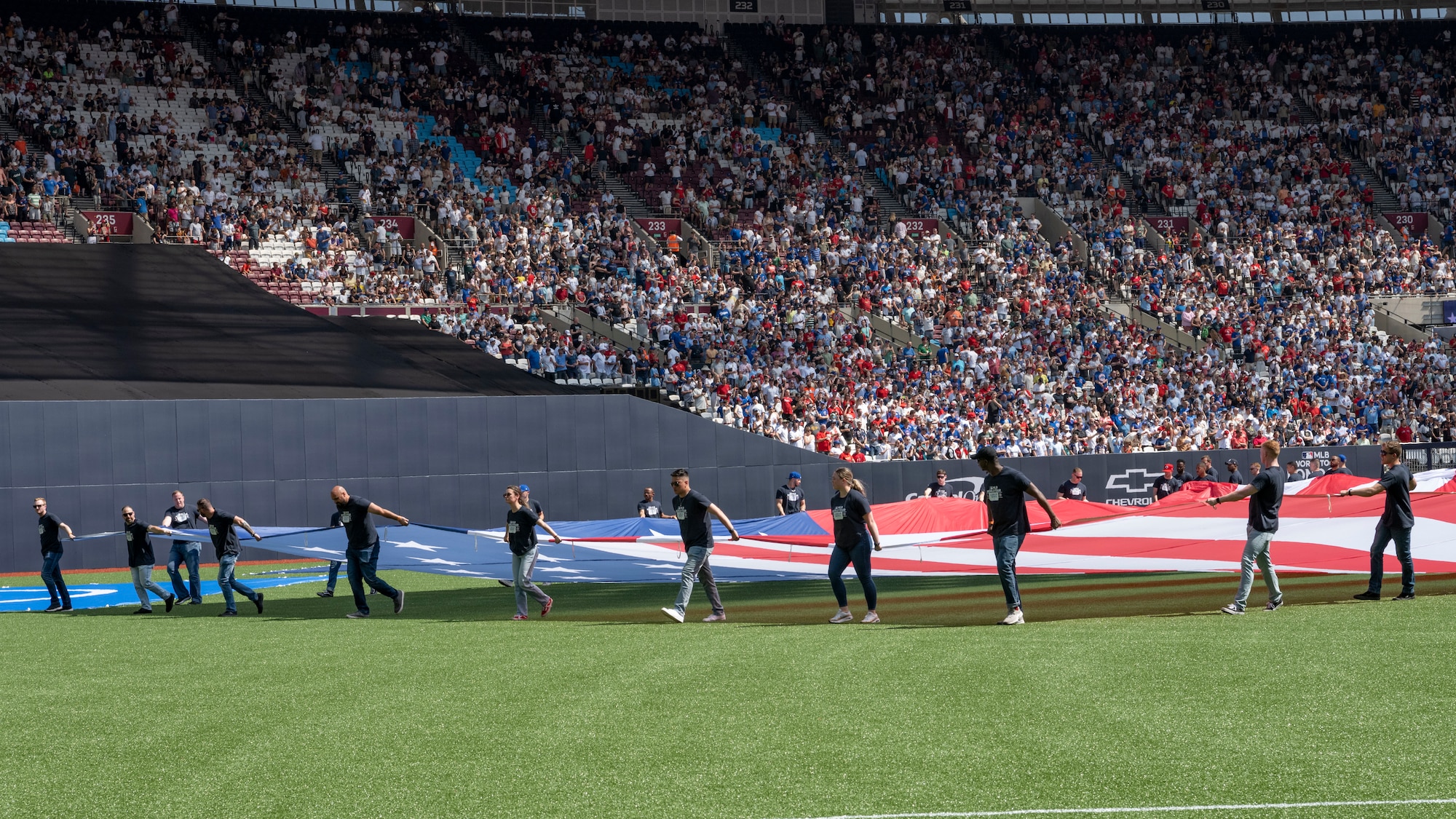 U.S. Air Force Airmen assigned to Royal Air Force Mildenhall unfurl a U.S. Flag on the field during the pre-game ceremony at London Stadium, England, June 25, 2023.