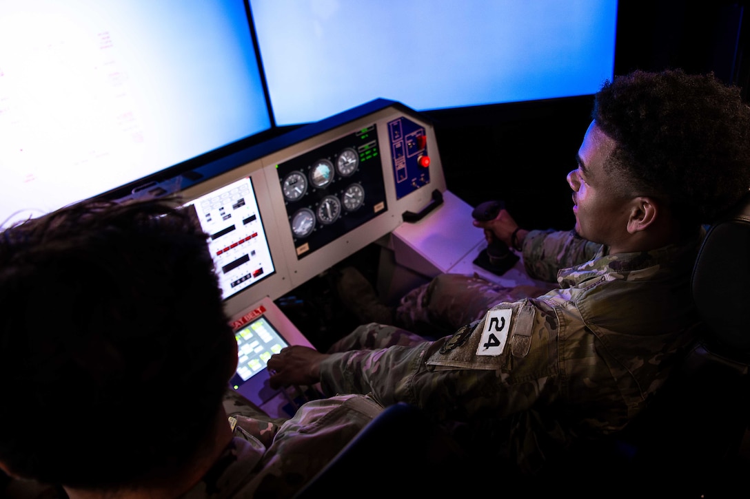 An airman sits at the controls of a flight simulator.