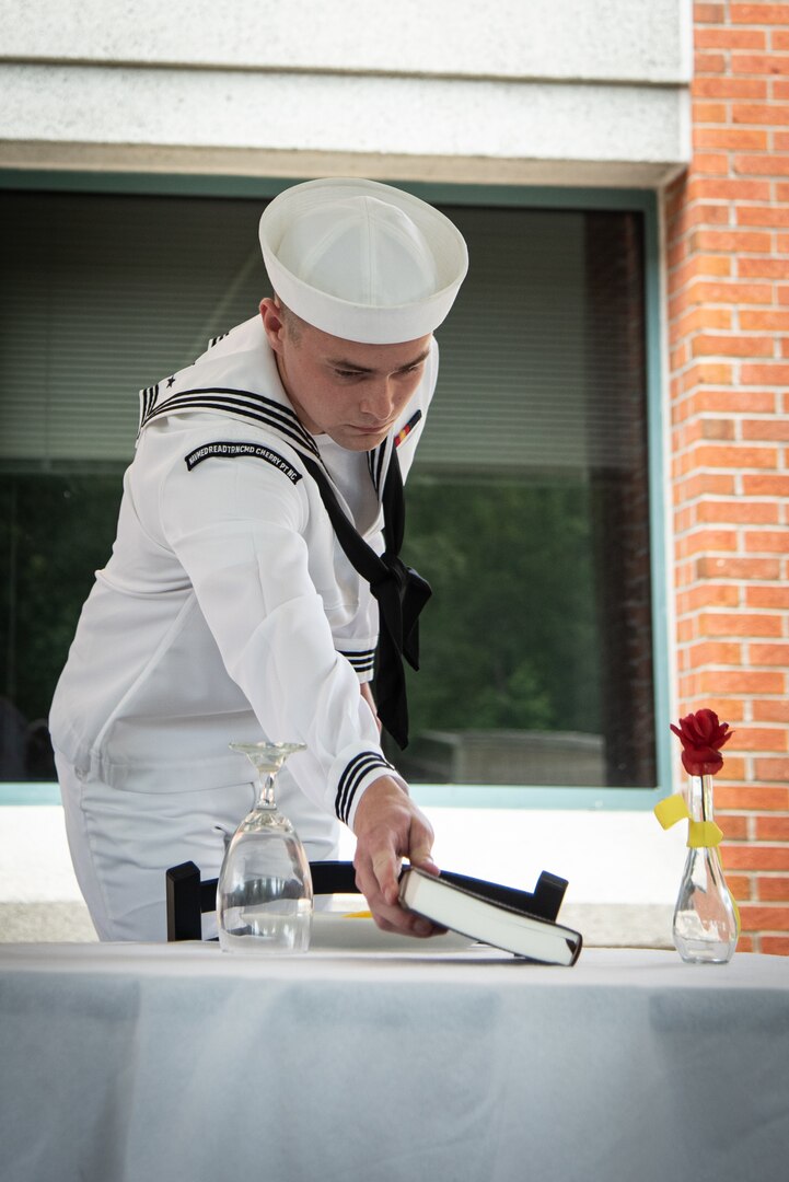 A Navy Hospital Corpsmen serving aboard Marine Corps Air Station Cherry Point places a Bible during a Missing Man Table and Honors Ceremony on Friday, June 16, 2023.  The ceremony was part of the installation’s celebration of the 125th Birthday of the Navy Hospital Corpsman.