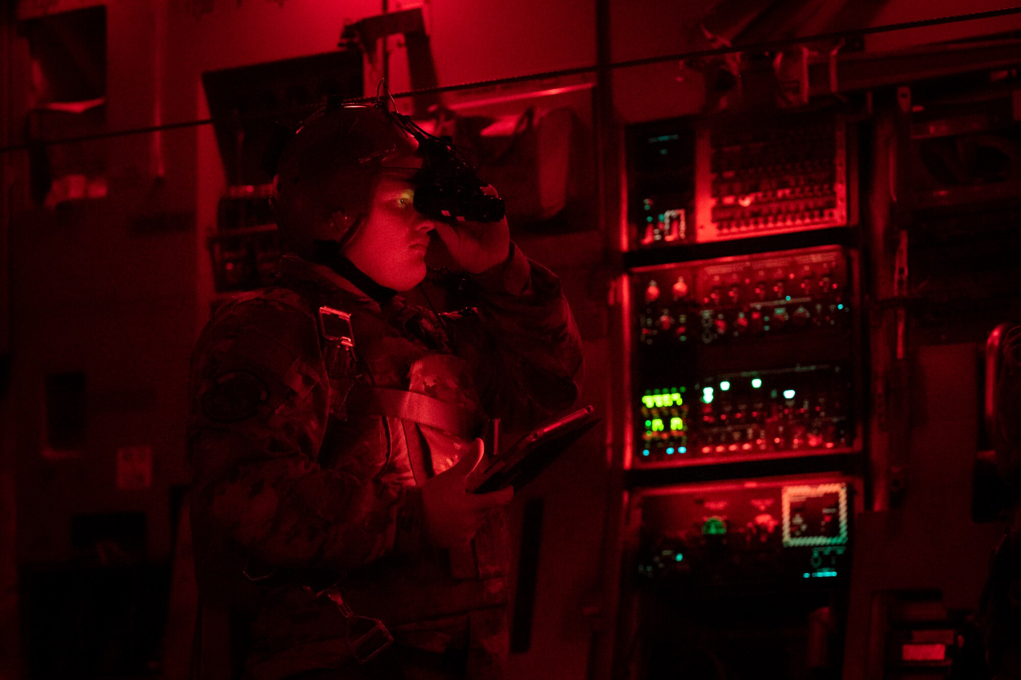 Military member in uniform equips night vision goggles to their head.