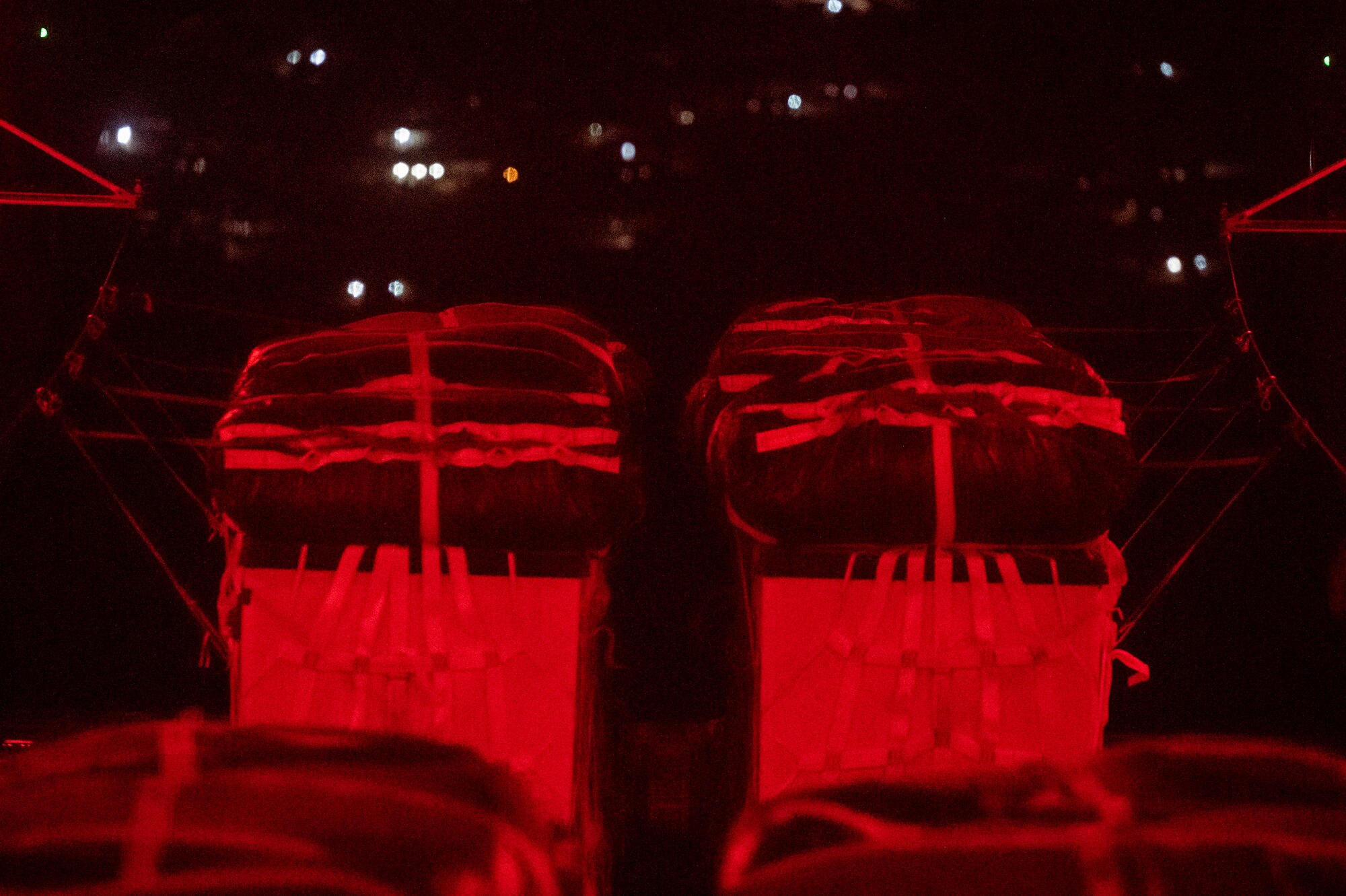 Two cargo crates drop off the ramp of an aircraft.