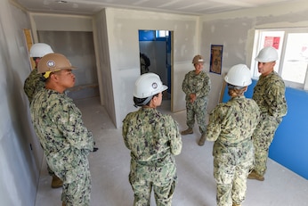Petty Officer 1st Class Cassandra Begay explains construction aspects of a newly built home to visiting leadership as part of a charitable contribution and training opportunity in partnership with the Southwest Indian Foundation.