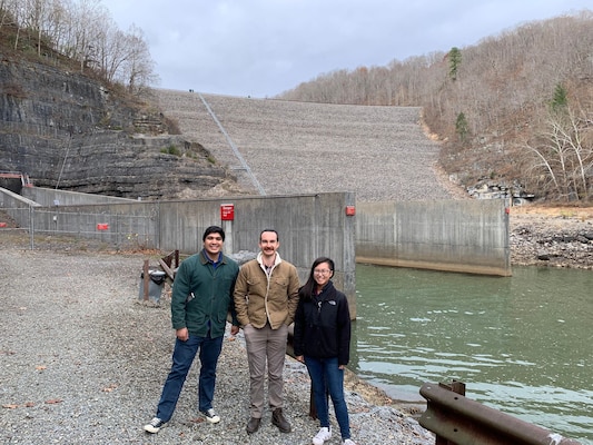 3 people standing in front of a dam.