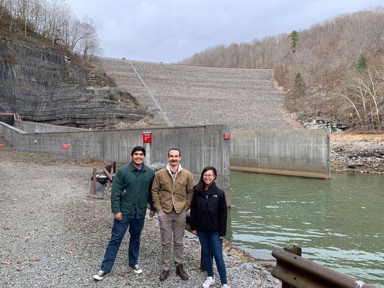 3 people standing in front of a dam.