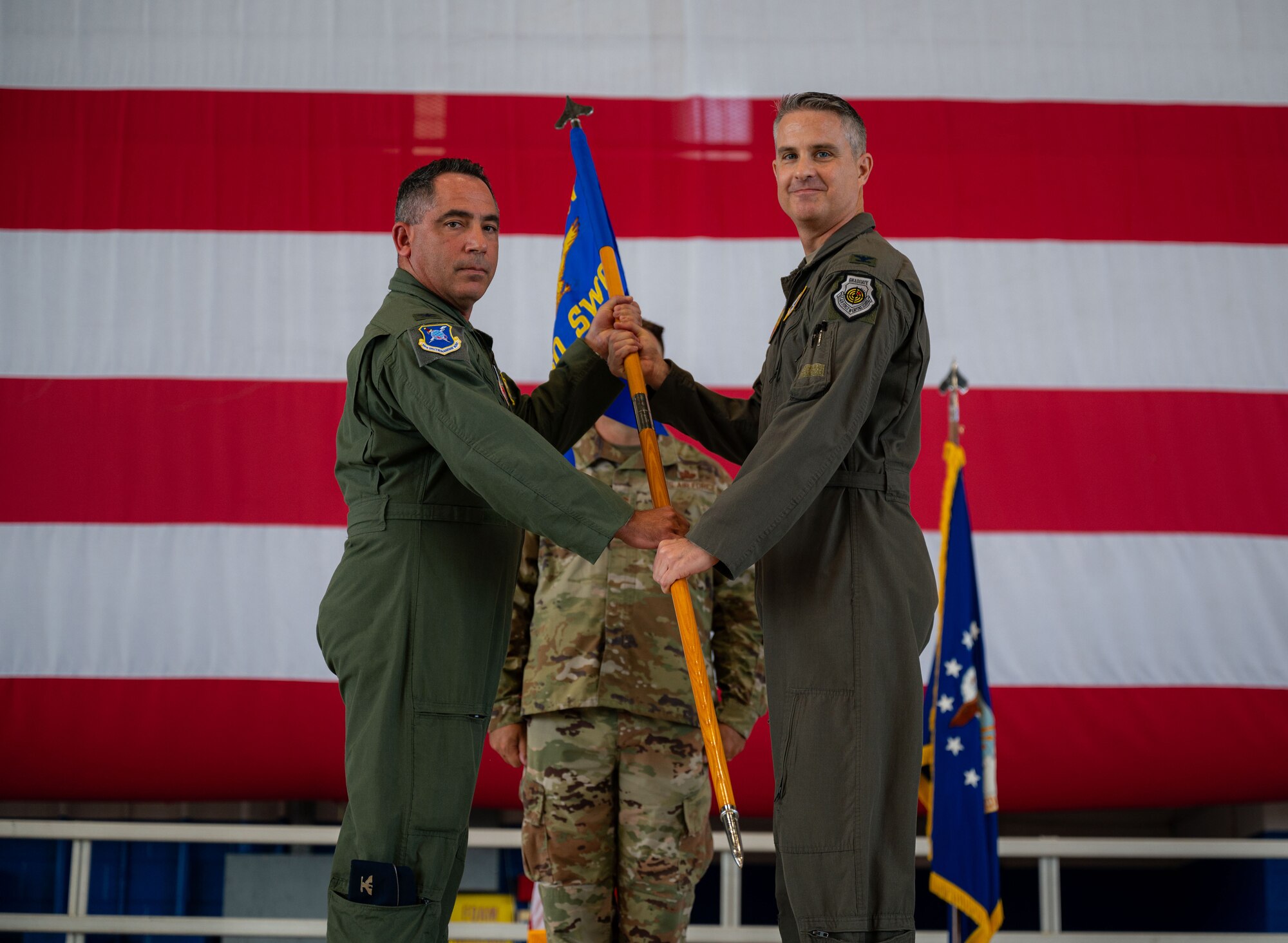 U.S. Air Force Col. Josh Koslov, 350th Spectrum Warfare Wing commander, left, holds the 850th Spectrum Warfare Group guidon with its new commander, U.S. Air Force Col. Andrew Finkler, right, during a change of command ceremony for the 850th Spectrum Warfare Group at Eglin Air Force Base, Fla., June 23, 2023. Finkler is the second commander for the 850th SWG, which was activated in 2021. (U.S. Air Force photo by 1st Lt. Benjamin Aronson)