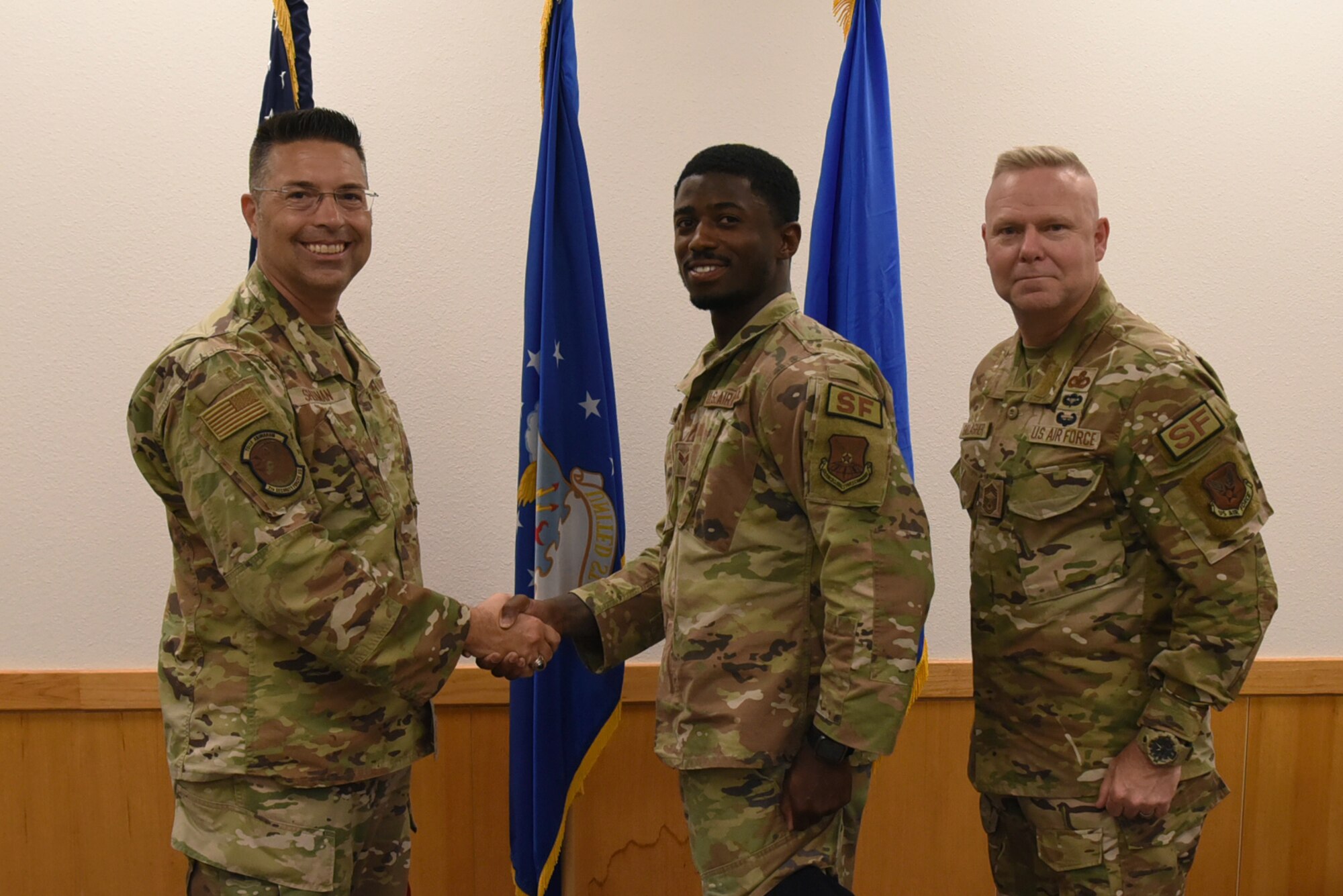 U.S. Air Force Brig. Gen. Thomas Sherman, Security Forces director, along with Chief Master Sgt. Donald Gallagher, Security Forces career field manager, presents a coin to Senior Airman Frederick Lawrence, 7th Security Forces Squadron physical security section lead, at Dyess Air Force Base, Texas, June 15, 2023. Sherman visited Dyess to present the 7th SFS with the Air Force Best Medium Sized Security Forces Squadron Award along with seeing new innovations including the robotic dog, a new GPS system, upgraded flack vests and more. (U.S. Air Force photo by Senior Airman Sophia Robello)