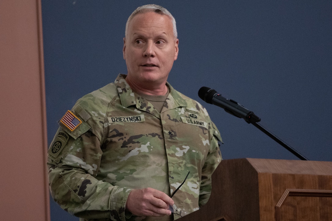 Brig. Gen. Joseph Dziezynski, outgoing MIRC commanding general, addresses Soldiers and guests from behind a podium.