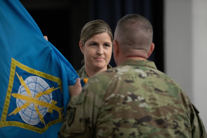 Col. Melissa Adamski accepts the MIRC colors from Cmd. Sgt. Maj. Brian Bertazon.