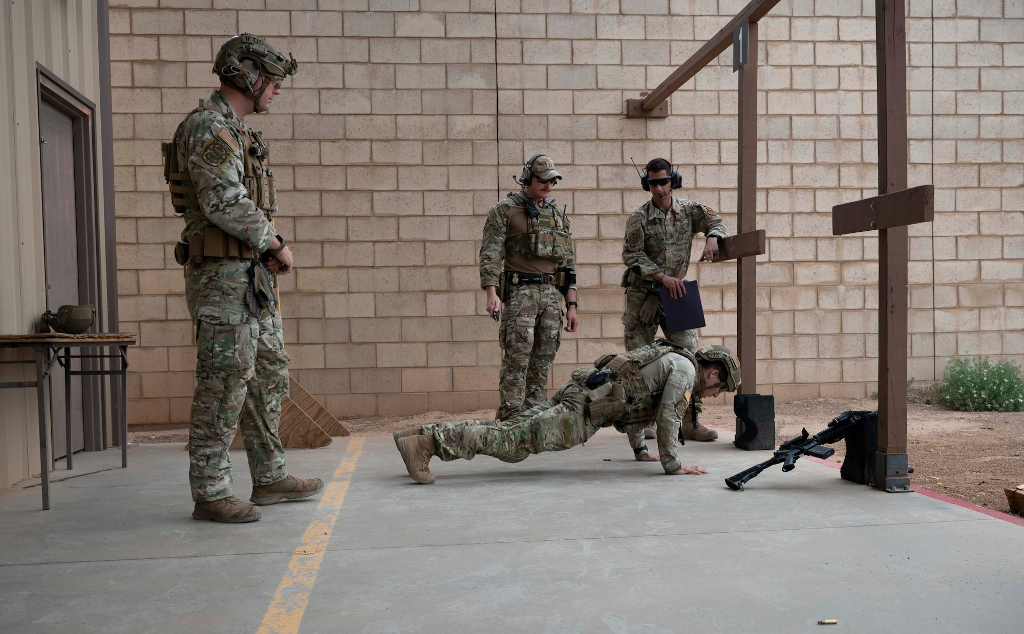 U.S. Air Force Staff Sgt. Lucas Fenwick, center, 49th Security Forces Squadron Base Defense Operations Center controller and traffic investigator, performs push ups as part of a Special Reactions Team assessment at Holloman Air Force Base, New Mexico, June 9, 2023. SRT tryouts determine the capability and accuracy of airmen who are qualified to handle high-risk crisis situations. (U.S. Air Force photo by Airman 1st Class Michelle Ferrari)