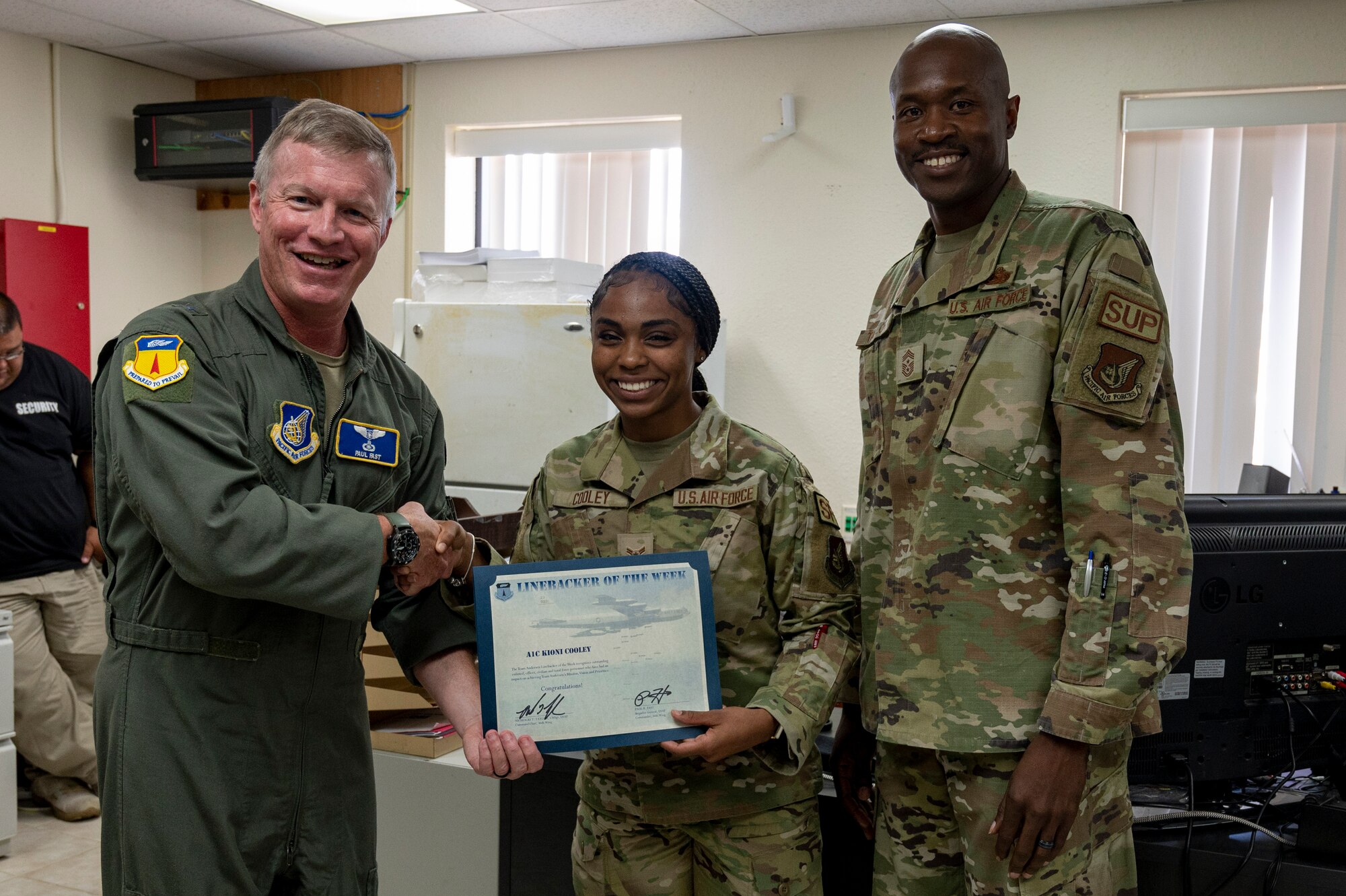 U.S. Air Force Airman 1st Class Kioni Cooley, an installation access clerk assigned to the 36th Security Forces Squadron, receives the Linebacker of the Week Award from U.S. Air Force Brig. Gen. Paul Fast, commander of the 36th Wing, and U.S. Air Force Chief Master Sgt. Nicholas Taylor, the command chief of the 36th Wing, at Andersen Air Force Base, Guam, June 21, 2023. The Team Andersen Linebacker of the Week recognizes outstanding enlisted, officer, civilian and total force personnel who have had an impact on achieving Team Andersen’s mission, vision and priorities. (U.S. Air Force photo by Airman 1st Class Emily Saxton)