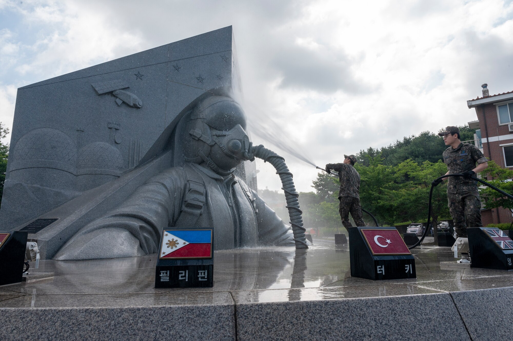 Republic of Korea Air Force Airmen spray down a memorial site at Osan Air Base, ROK, June 22, 2023. After the site was sprayed down, ROK and U.S. troops thoroughly cleaned the memorial to pay respects to those who made the ultimate sacrifice during the Korean War. (U.S. Air Force photo by Senior Airman Aaron Edwards)