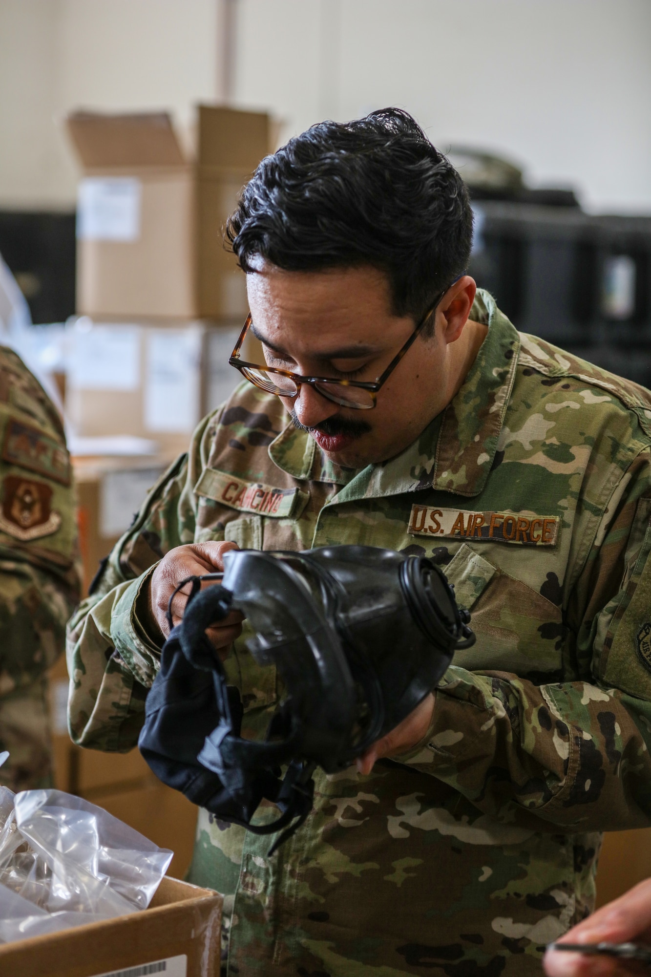 MSgt Diego Cancino, 445th Operations Support Squadron Aircrew Flight Equipment  Flight Chief, inspects a new M69 mask for any tears, defects, or other damage on June 7th, 2023. Boxes of these new CBRN masks were recently shipped to the 445th OSS and were inspected before being added to the shop inventory. The 445th OSS later held a training event for the 89th Airlift Squadron aircrew to deliver the necessary training and answer questions that aircrew members might have about the new aircrew CBRN mask, the JSAM SA.