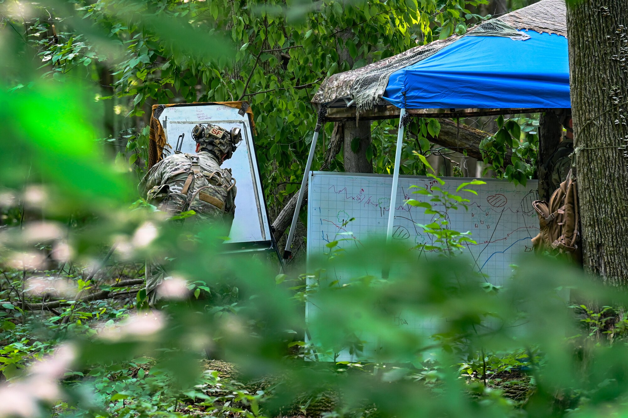 A Defender assigned to the 301st Security Forces Squadron, Carswell Field, Naval Air Station Joint Reserve Base Fort Worth, Texas, writes detailed strategic information for a training exercise on a dry-erase board on June 15, 2023, at Camp James A. Garfield Joint Military Training Center, Ohio.