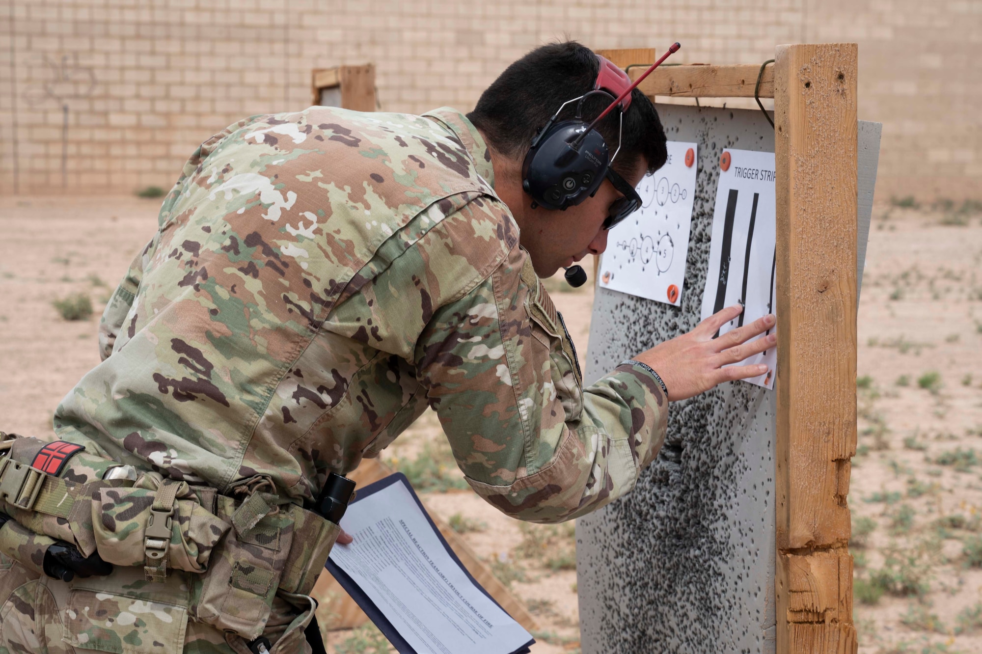 U.S. Air Force Staff Sgt. Chandler Docusen,  49th Security Forces Squadron unit trainer, inspects a target for accuracy during Special Reactions Team tryout at Holloman Air Force Base, New Mexico, June 9, 2023. SRT tryouts determine the capability and accuracy of airmen who are qualified to handle high-risk crisis situations. (U.S. Air Force photo by Airman 1st Class Michelle Ferrari)