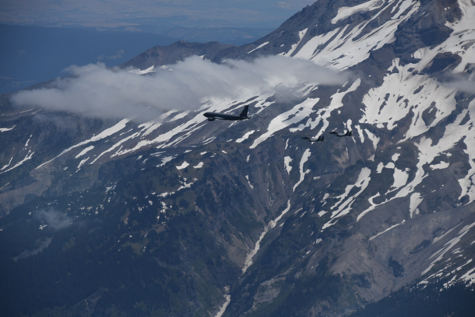 A U.S. Air Force KC-135 Stratotanker assigned to the 92nd Air Refueling Wing flies in formation with two F-15C Eagles from the 142nd Fighter Wing over Mount Rainier during Operational Centennial Contact June 27, 2023. Operation Centennial Contact, a movement which included flights over Yellowstone National Park, Mount Rushmore and Glacier National Park, was part of Air Mobility Command’s celebration of 100 years air refueling operations and demonstrated the 92nd Air Refueling Wing’s global reach capabilities. Since its inception in 1923, air refueling has become a crucial component of military and civilian aviation operations around the world by extending the range and endurance of aircraft and enabling them to complete missions that would otherwise be impossible or require multiple stops. As a result, this capability is essential for strategic and tactical operations, as well as humanitarian relief efforts in support of AMC, U.S. Transportation Command and Department of Defense priorities. (U.S. Air Force Photo by 1st Lt. Ariana Wilkinson)
