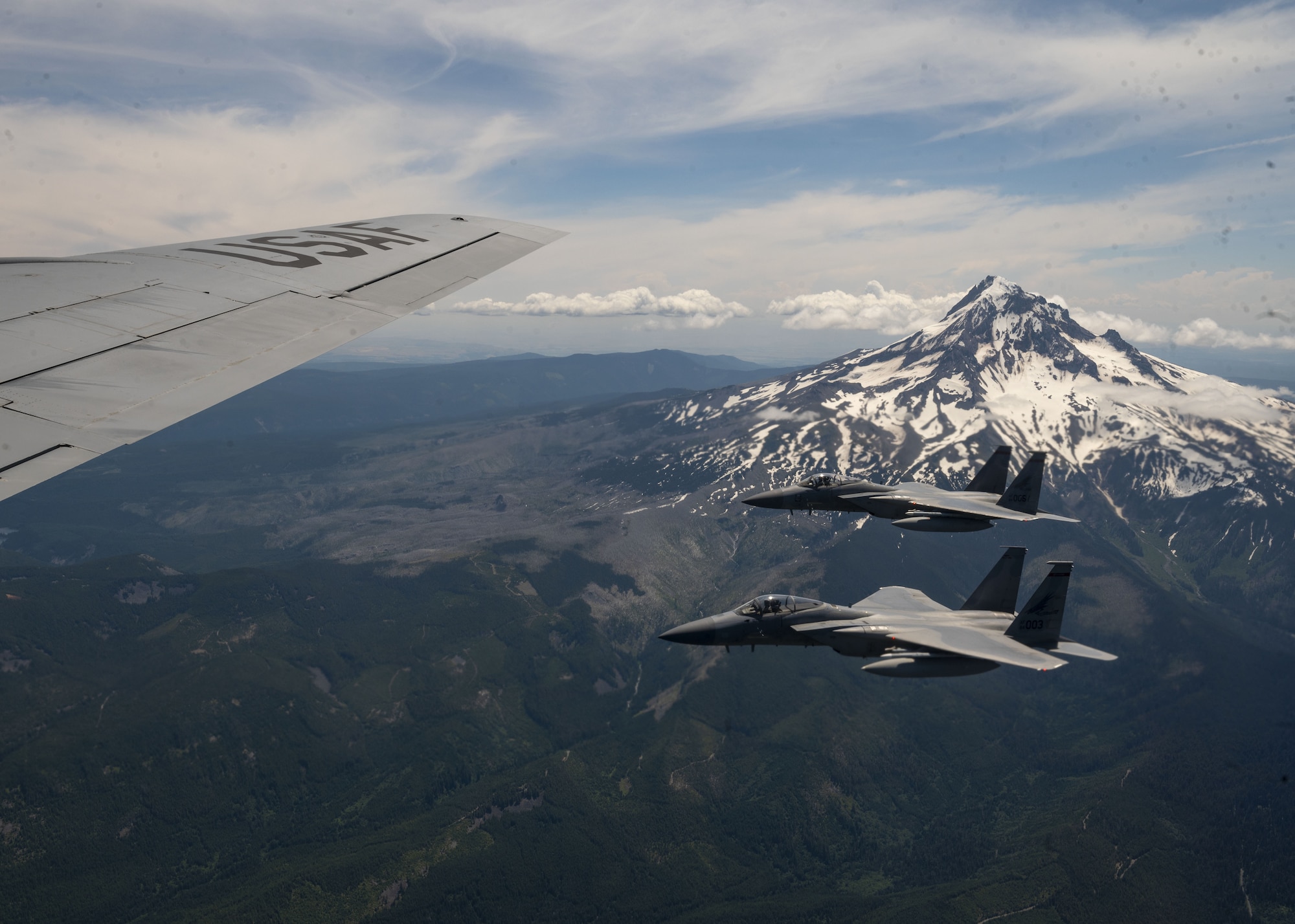F-15C Eagles fly near a KC-135 Stratotanker assigned to the 92nd Air Refueling Wing over Mount Hood in Oregon as part of Operation Centennial Contact June 27, 2023. The movement, which also included flights over Yellowstone National Park, Mount Rushmore and Glacier National Park, was part of Air Mobility Command’s celebration of 100 years air refueling operations and demonstrated the 92nd Air Refueling Wing’s global reach capabilities. Since its inception in 1923, air refueling has become a crucial component of military and civilian aviation operations around the world by extending the range and endurance of aircraft and enabling them to complete missions that would otherwise be impossible or require multiple stops. As a result, this capability is essential for strategic and tactical operations, as well as humanitarian relief efforts in support of AMC, U.S. Transportation Command and Department of Defense priorities. (U.S. Air Force photo by Staff Sgt. Lawrence Sena)