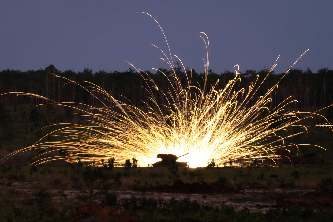 Fire and sparks rise into the air following an explosion at night.