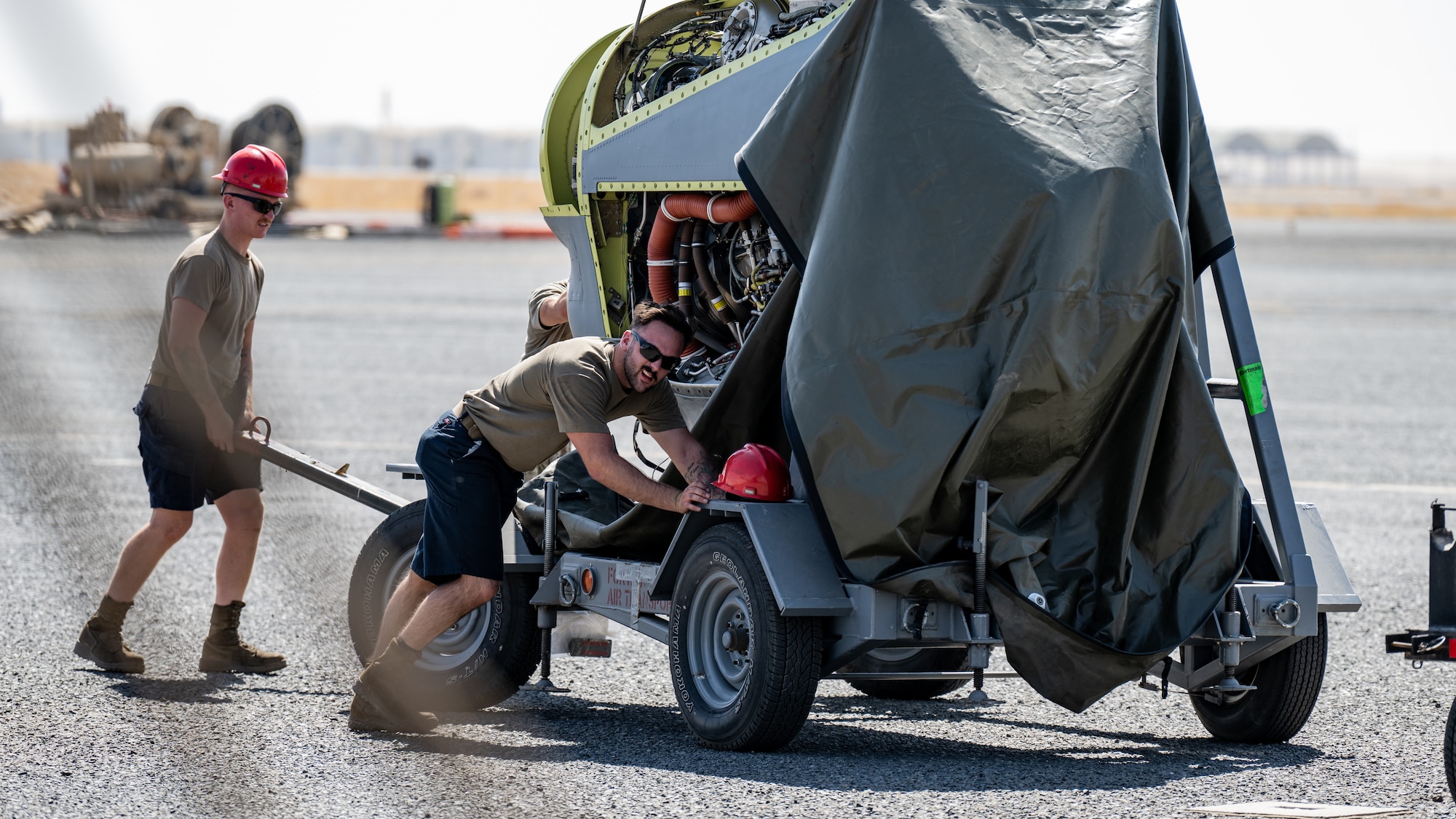 Senior Airman Austin Willard and Senior Airman Steven Garland, 386th Expeditionary Aircraft Maintenance Squadron aerospace propulsion technicians, move an engine towards a C-130J Super Hercules at Ali Al Salem Air Base, Kuwait, June 27, 2023. The 386th Air Expeditionary Wing is the primary airlift hub and gateway for delivering combat power to joint and coalition forces in the U.S. Central Command area of responsibility. (U.S. Air Force photo by Staff Sgt. Kevin Long)