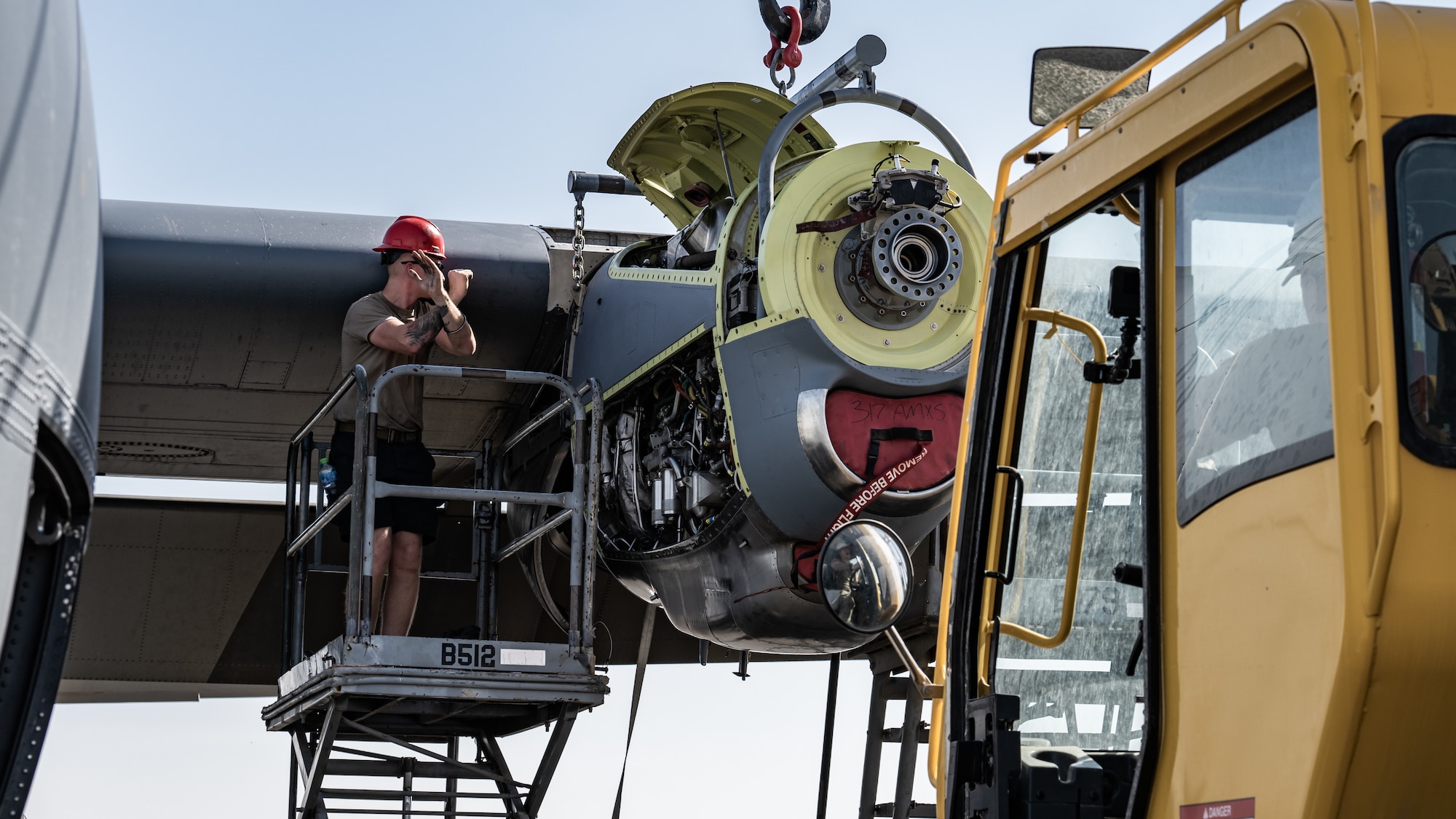 Senior Airman Austin Willard, 386th Expeditionary Aircraft Maintenance Squadron aerospace propulsion technician, signals to a crane operator during a C-130J Super Hercules engine swap at Ali Al Salem Air Base, Kuwait, June 27, 2023. The 386th EAMXS ensures their aircraft are always ready to deliver world-class warfighter support as a key airlift and airdrop enabled asset. (U.S. Air Force photo by Staff Sgt. Kevin Long)