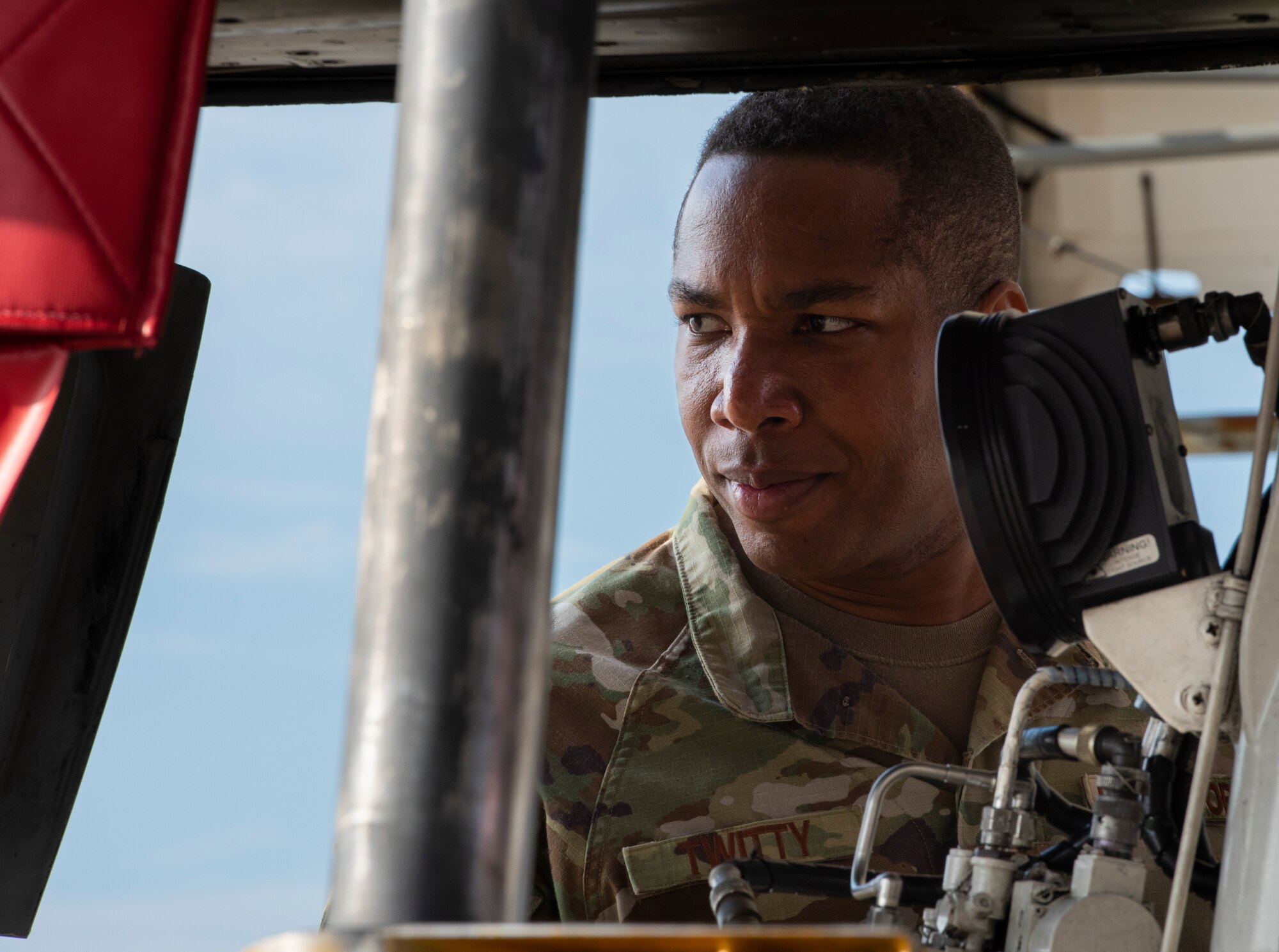 A photo of a person looking to the left of the screen, they are framed by aircraft parts in the photo.