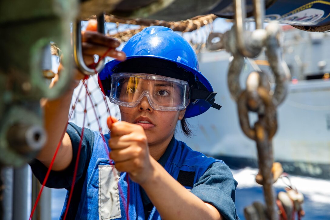 A sailor in a hard hat participates in a replenishment at sea.