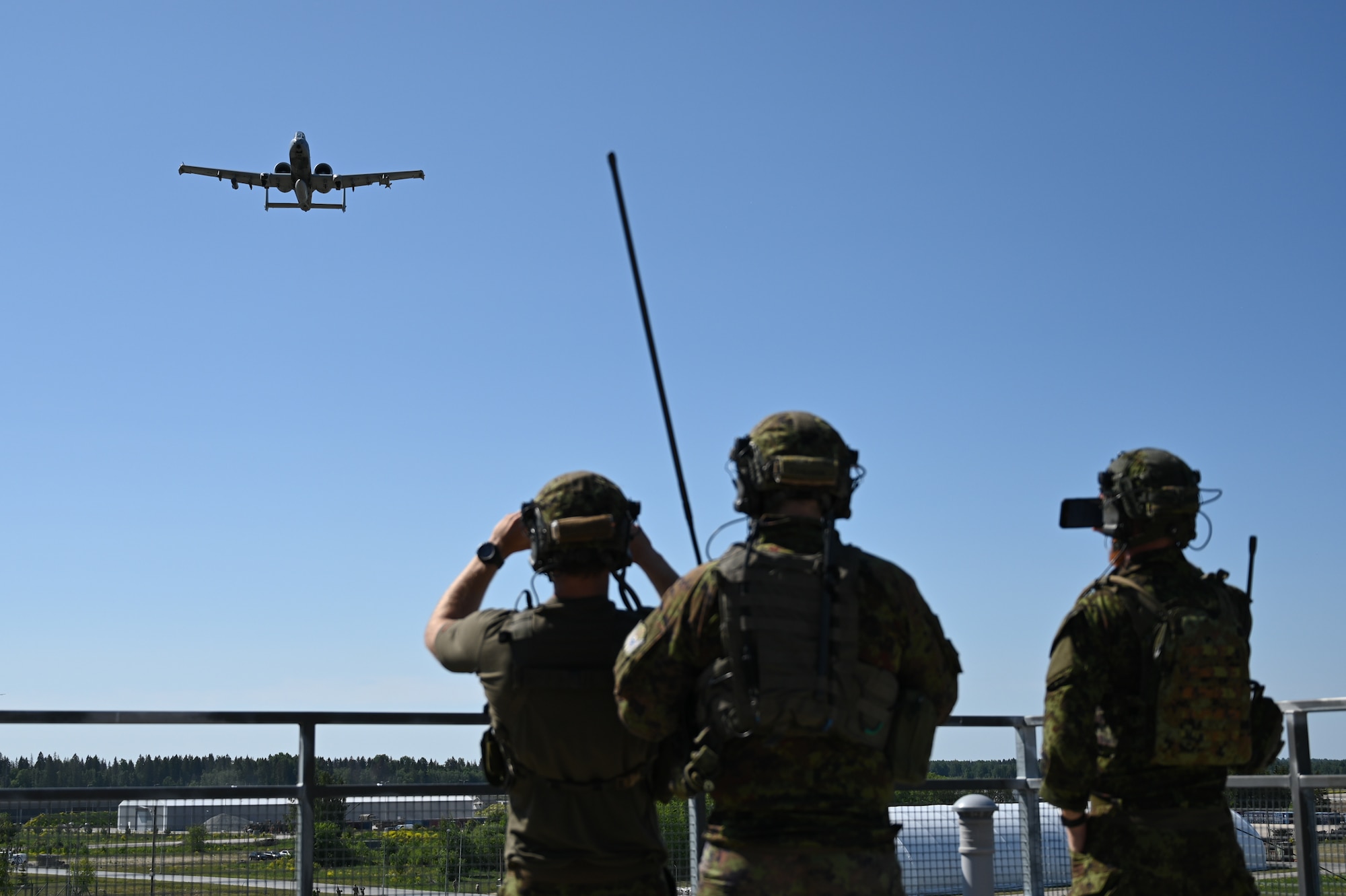 Estonian joint terminal attack controllers watch a U.S. Air Force A-10C Thunderbolt II aircraft assigned to the 104th Fighter Squadron, 175th Wing, Maryland National Guard, perform a show of force after completion of a training sortie, June 14, 2023, at Tapa Army Base, Estonia.