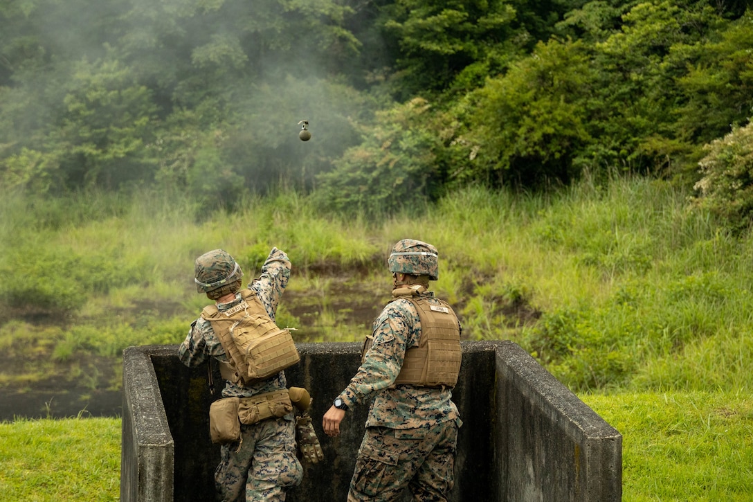 U.S. Marine Corps Lance Cpl. Hunter Wheatley, left, a motor vehicle operator with Combat Logistics Battalion 4, Combat Logistics Regiment 3, 3rd Marine Logistics Group, throws an M67 grenade while being directed by Sgt. Maj. Jaime Lerma, right, the sergeant major of CLB-4 during an M67 Grenade range on Combined Arms Training Center Fuji, June 23, 2023. CLB-4 conducted a grenade range to foster force readiness and condition warfighting skills.