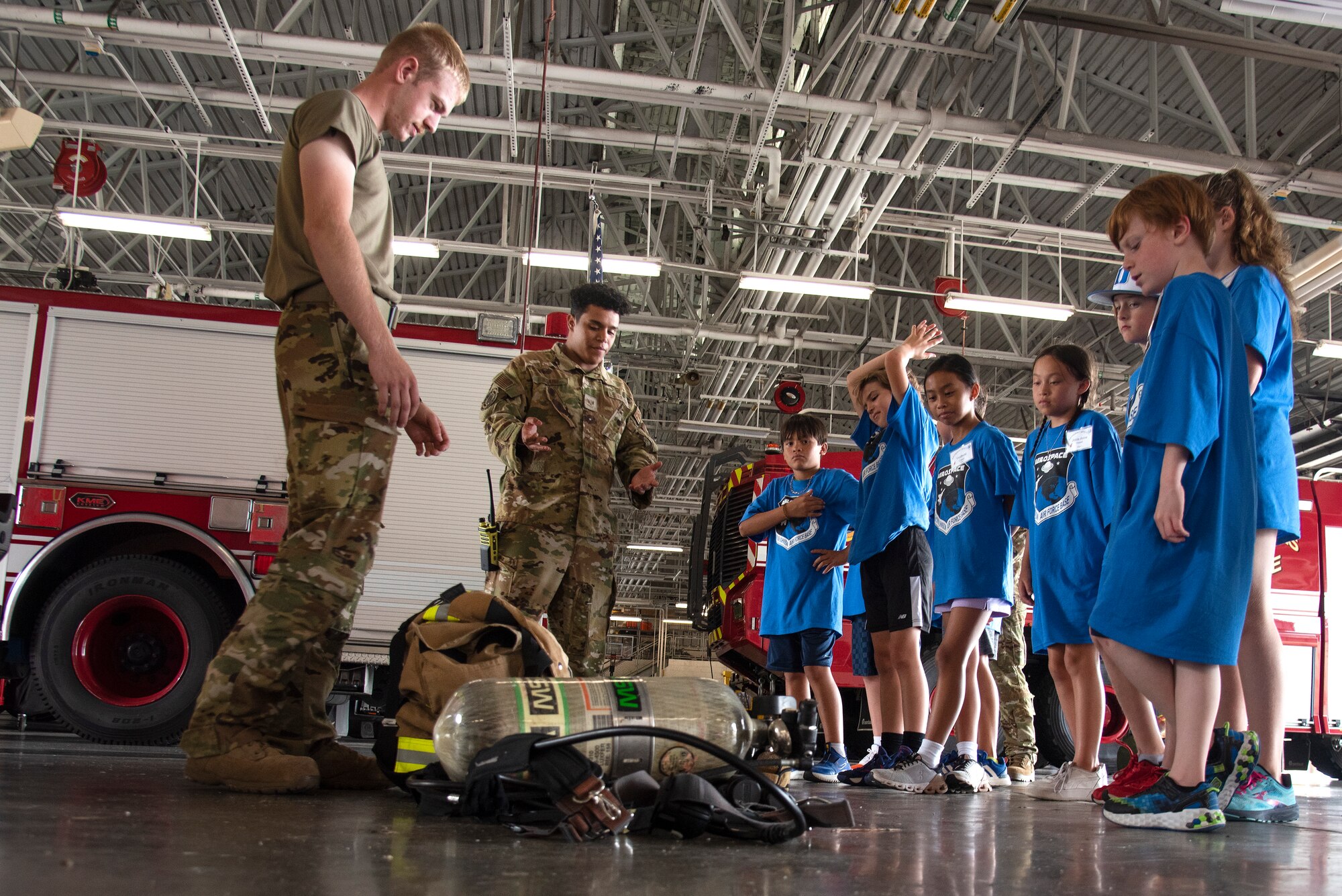 Senior Airman Marwane Hsaini, center left, and Airman Jaycob Stanley, left, 4th Civil Engineer Squadron firefighters, show Wayne County students how to don firefighting personal protective equipment during an Aerospace Camp community event at Seymour Johnson Air Force Base, North Carolina, June 20, 2023. The Aerospace Camp gave students an opportunity to meet Airmen who use science, technology, engineering and math (STEM) when performing their mission, and tour locations on base to learn how Team Seymour contributes to the Air Combat Command and U.S. Air Force mission. Community events like this help strengthen the partnership shared between the base and local community, and develop our youth to progress as future leaders. (U.S. Air Force photo by Tech. Sgt. Christopher Hubenthal)