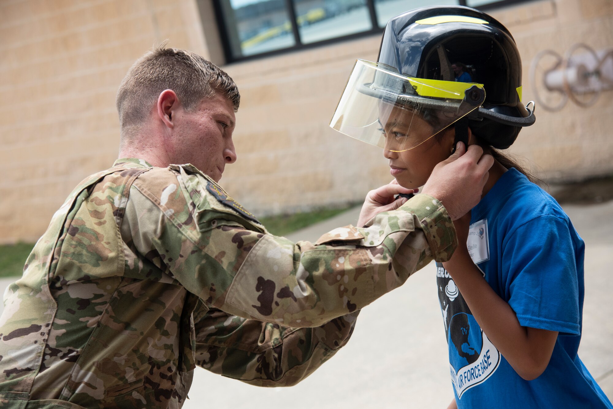 Airman 1st Class Tyler Johnson, 4th Civil Engineer Squadron firefighter, helps a Wayne County student put on a fire fighting helmet during an Aerospace Camp community event at Seymour Johnson Air Force Base, North Carolina, June 20, 2023. The Aerospace Camp gave students an opportunity to meet Airmen who use science, technology, engineering and math (STEM) when performing their mission, and tour locations on base to learn how Team Seymour contributes to the Air Combat Command and U.S. Air Force mission. Community events like this help strengthen the partnership shared between the base and local community and develop our youth to progress as future leaders. (U.S. Air Force photo by Tech. Sgt. Christopher Hubenthal)