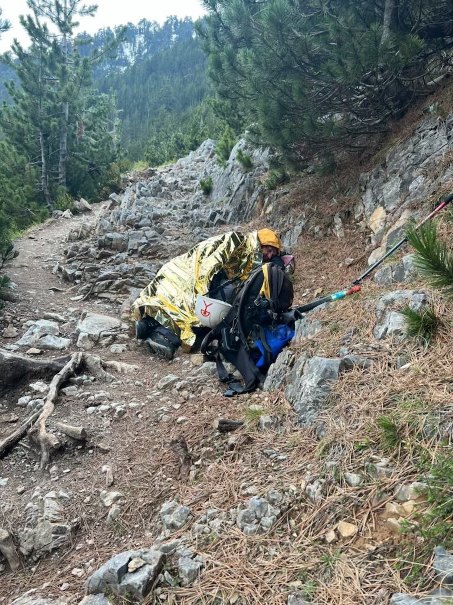 A view of Mt. Olympus with a man lying on the ground in gold metallic blanket for warmth.