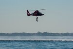 A Coast Guard Air Station Savannah MH-65 Dolphin helicopter crew hoists a water rescue dummy during a mass rescue exercise in the Port of Charleston, South Carolina, June 28, 2023.