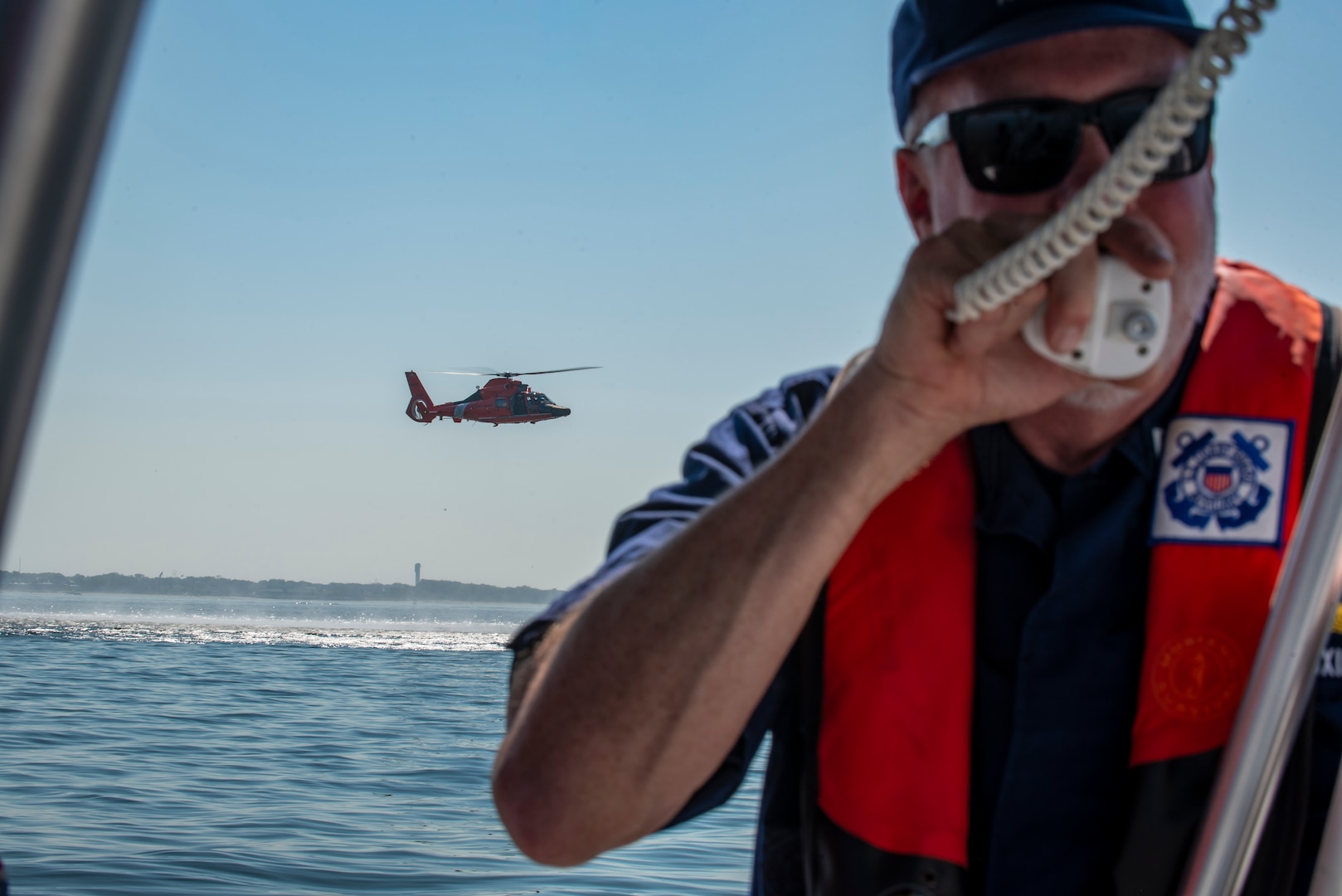 A Coast Guard Auxiliary member and a Coast Guard Air Station Savannah MH-65 Dolphin helicopter crew participate in a mass rescue exercise in the Port of Charleston, South Carolina, June 28, 2023.