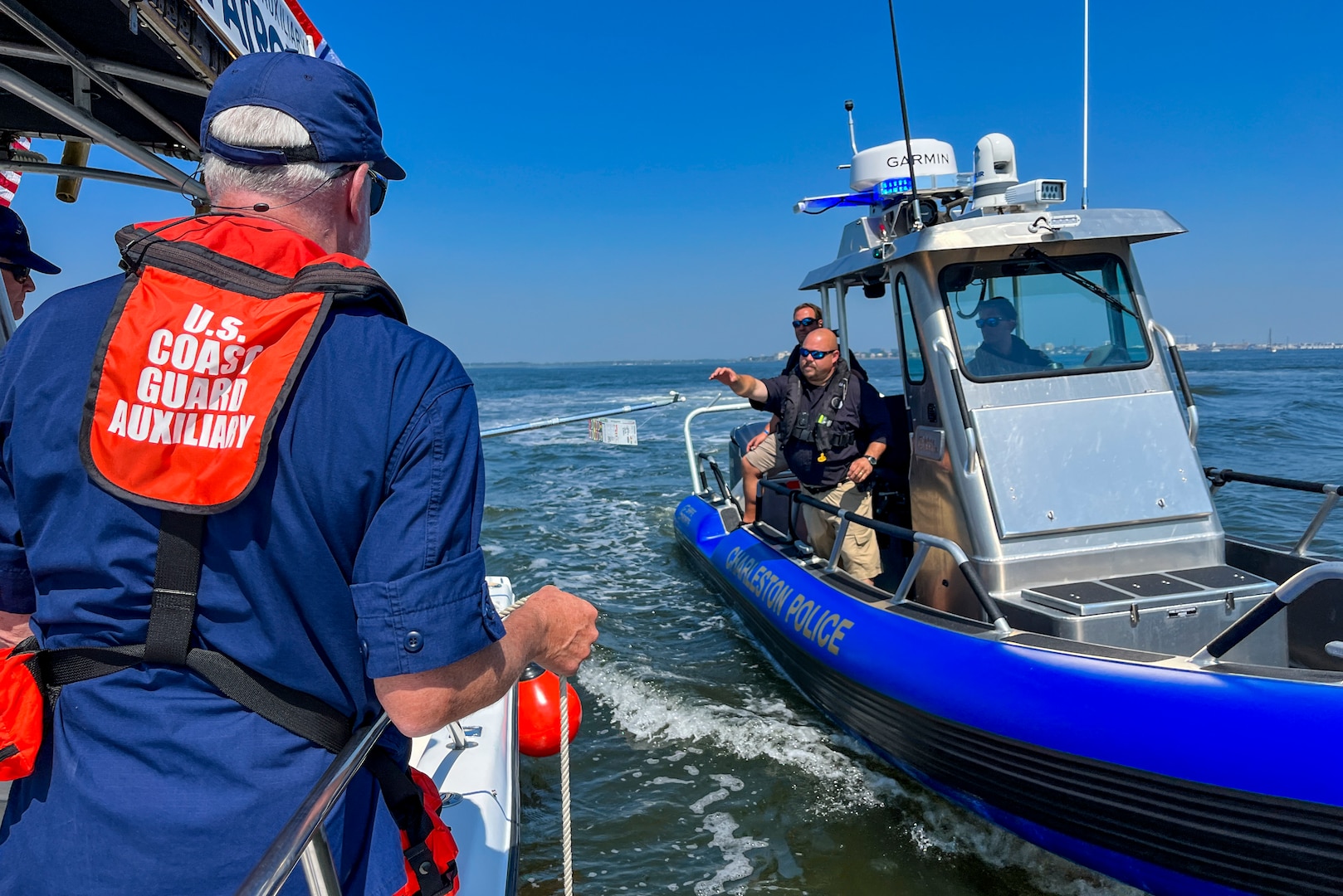 A Charleston Police Department boat crew member retrieves a survivor scenario card from a Coast Guard Auxiliary boat crew during a mass rescue exercise in the Port of Charleston, South Carolina, June 28, 2023.