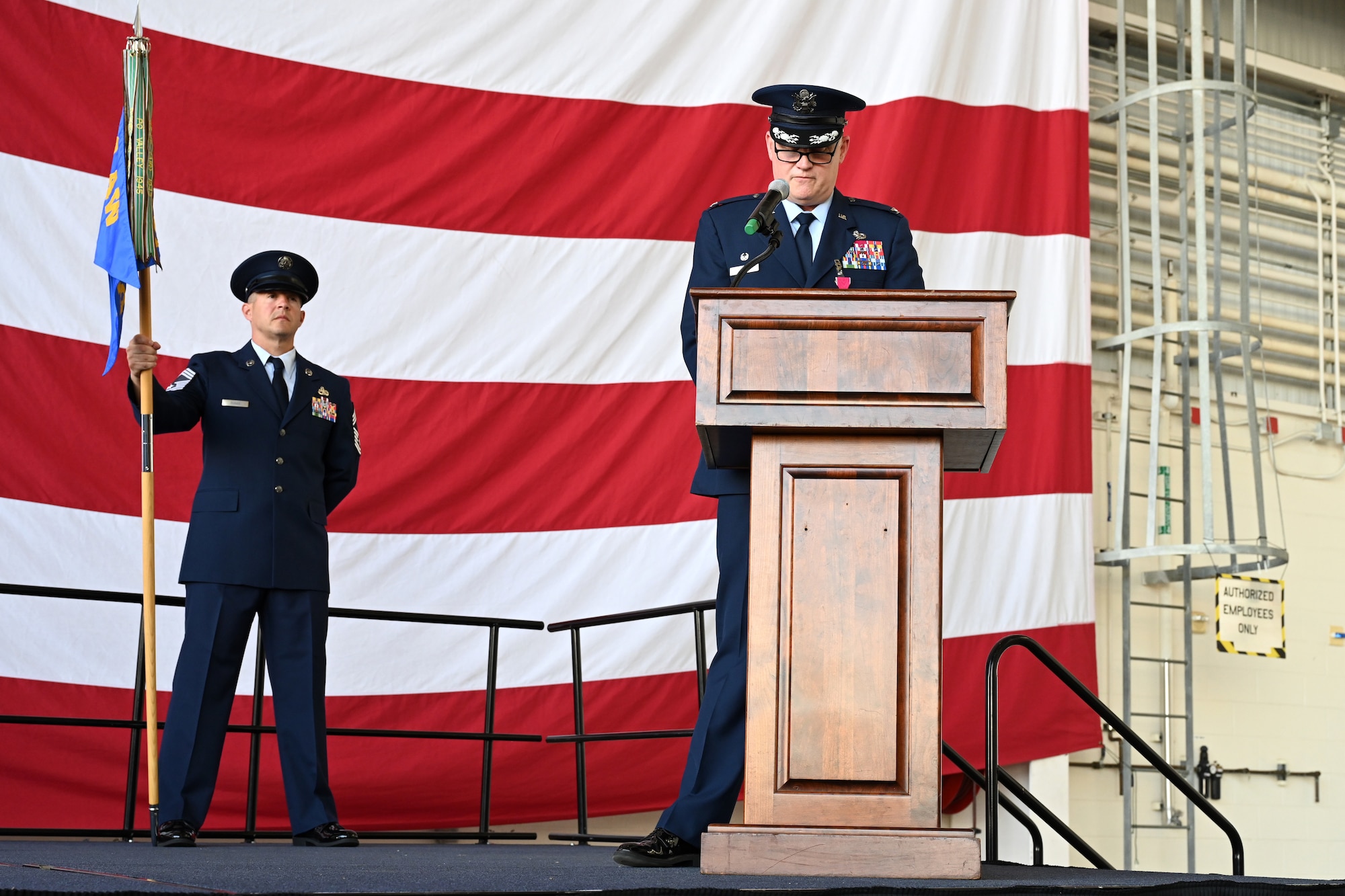 The 19th Maintenance Group performs a change of command ceremony in an airplane hangar
