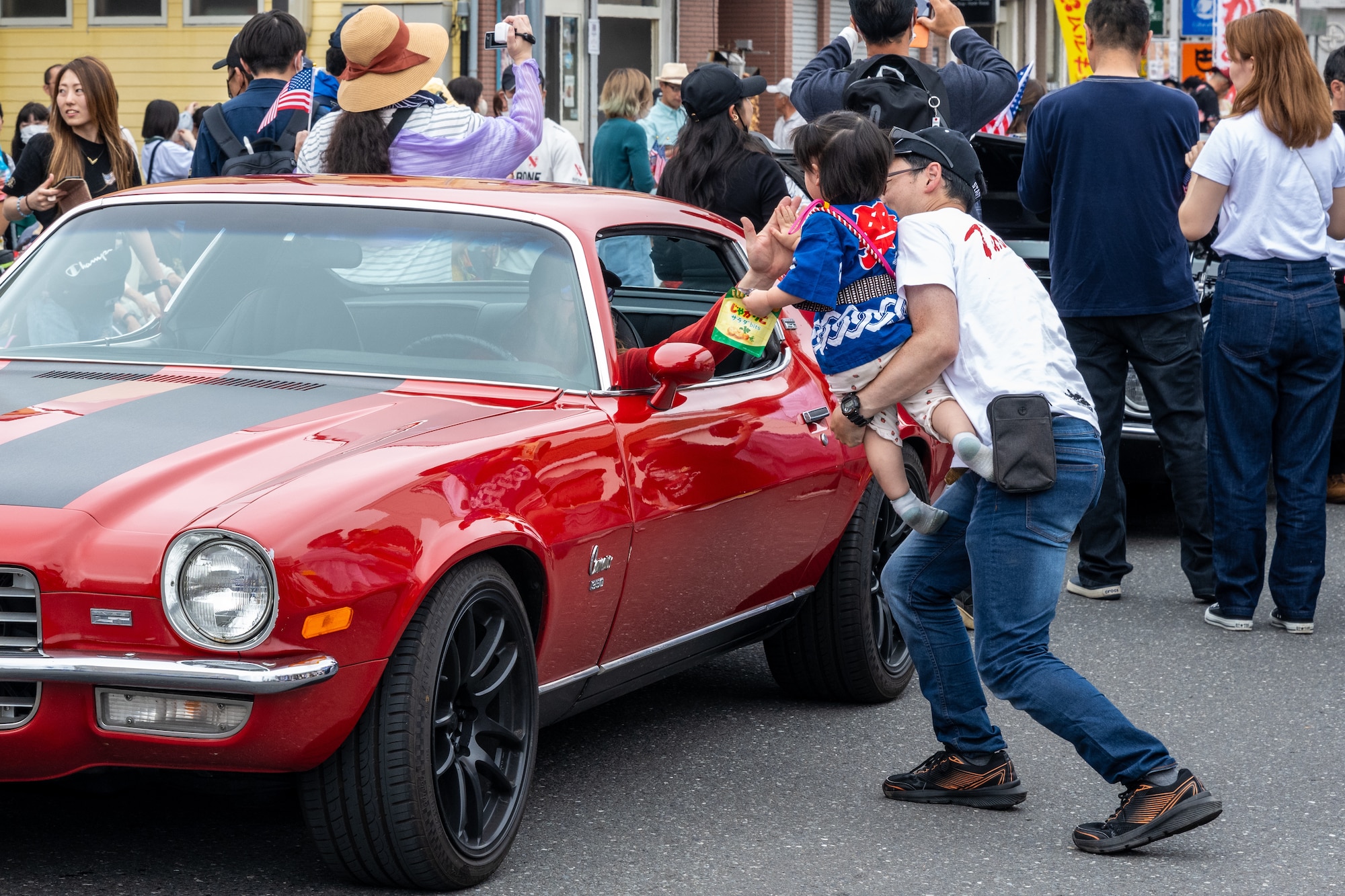 Japanese and American attendees of American Day exchange greetings during the parade in Misawa City, Japan, June 25, 2023. Events like these are important as they afford Misawa’s local community, American and Japanese alike, opportunities to interact in a relaxed environment meant to build friendships and strengthen partnerships. (U.S. Air Force photo by Staff Sgt. Kristen Heller)