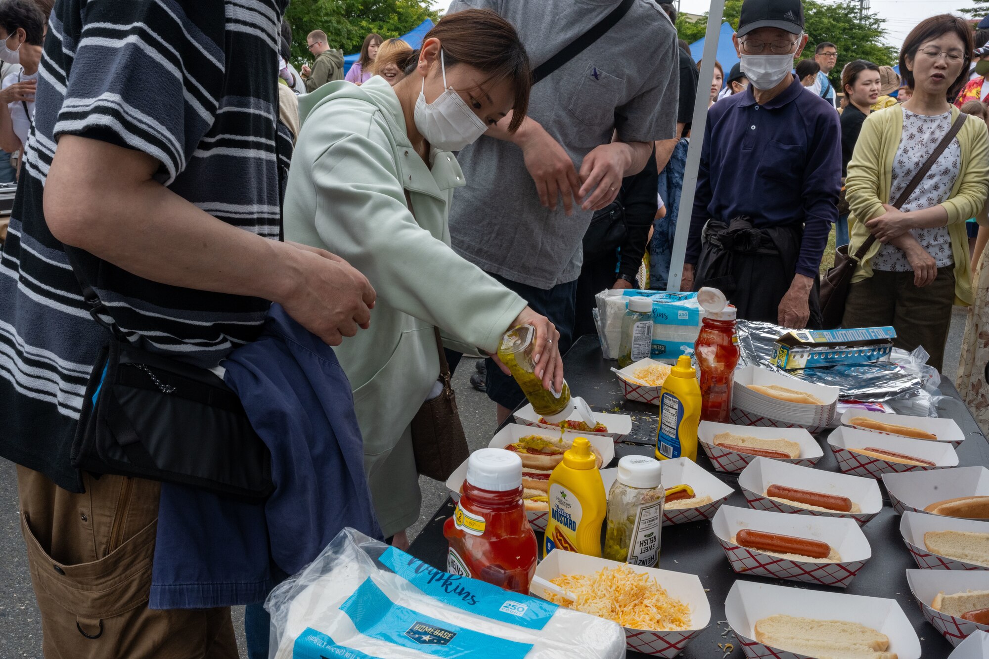 Japanese attendees dress their hotdogs during American Day in Misawa City, Japan, June 25, 2023. Events like these are important as they afford Misawa’s local community, American and Japanese alike, opportunities to interact in a relaxed environment meant to build friendships and strengthen partnerships. (U.S. Air Force photo by Staff Sgt. Kristen Heller)