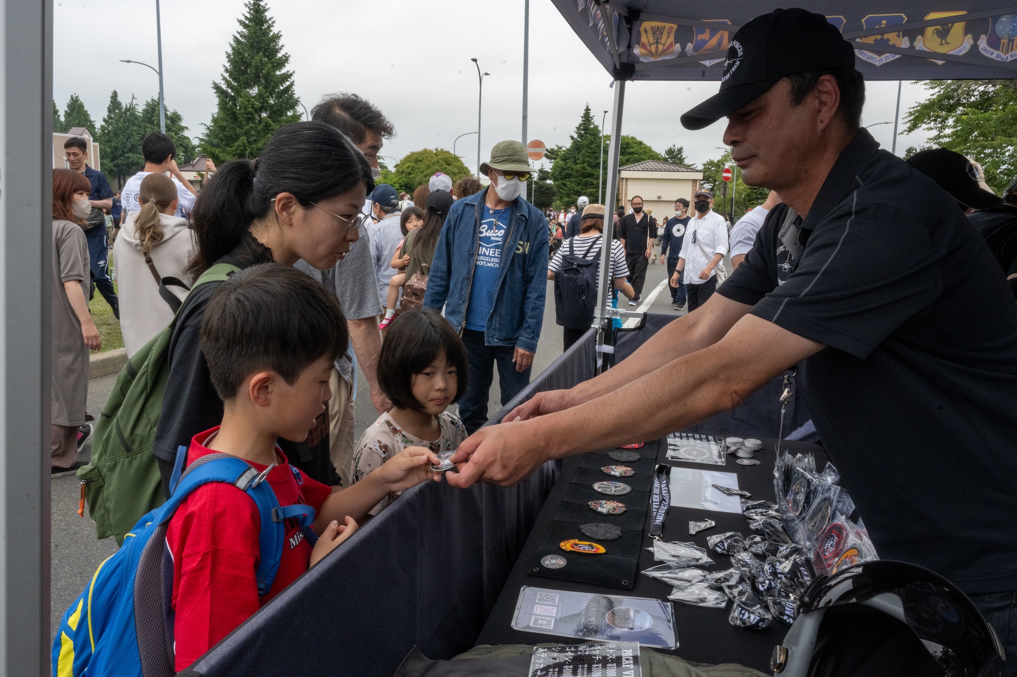 PACAF F-16 Demonstration Team stickers are handed out to attendees of American Day in Misawa City, Japan, June 25, 2023. American Day is one of the largest cross-cultural festivals in the area and it made a return after being on hiatus due to COVID-19. The event, drawing over 50,000 visitors, took on the theme “two cultures, but one community.” (U.S. Air Force photo by Staff Sgt. Kristen Heller)